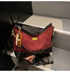 Dettaglio borsa in camoscio bordeaux trapuntato con base in pelle nera e chiusura dorata