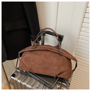 Detail of brown suede large tote bag with embossed PANTOUR logo on a silver suitcase