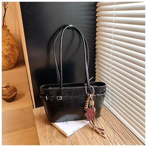 Detail of black glossy underarm bag with silver buckles and a cute red heart bear charm