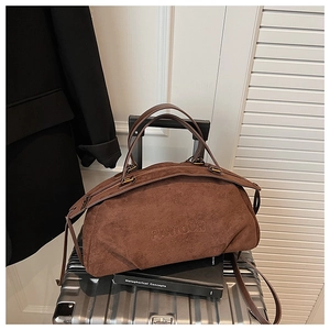 Detail of dark brown suede travel bag with brand embossing on metal suitcase