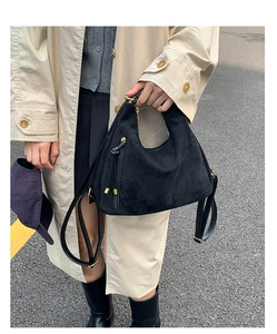 Detail of matte black hobo bag with gold hardware shown in a street lifestyle setting
