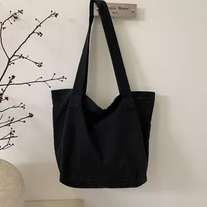 Detail shot of a minimalist black canvas tote bag hanging with large capacity and straps