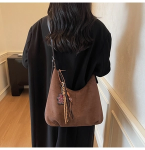 Vue arrière du sac hobo en daim marron avec franges et breloque cœur léopard sur modèle