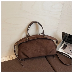 Close-up of vintage dark brown suede Boston bag with embossed logo on a bench