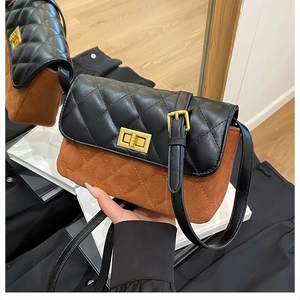 Detail of quilted leather and brown suede finish on a square crossbody bag with gold lock