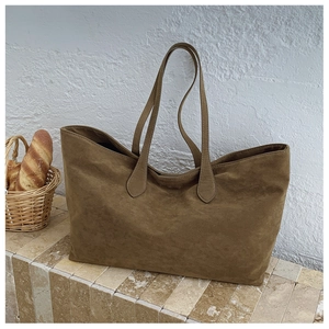 Macro view of textured brown suede tote bag featuring reinforced stitching and long straps