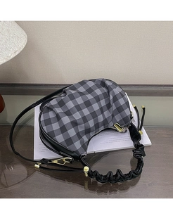 Detail of checkered hobo bag with pleated handle and adjustable leather strap on books