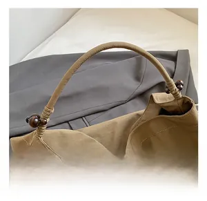 Détail du sac cabas kaki avec poignées tressées et perles décoratives en bois brun