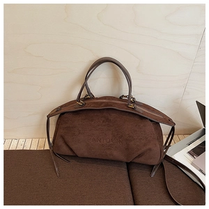 Detail of a dark brown suede Boston bag featuring the Pantour logo on wood background