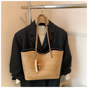 Détail du sac cabas camel avec matière texturée et pendentif à pampilles en bois