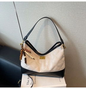 Dettaglio della borsa hobo in tela trapuntata bianca con finiture in pelle nera e perle