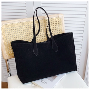 Minimalist black suede tote bag detail on a vintage chair with natural light ambiance