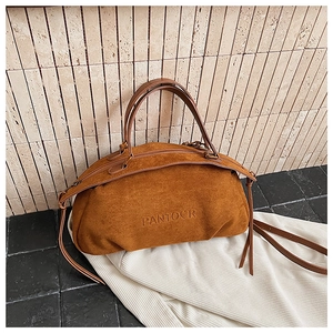 Detailed macro of dark brown suede pillow bag with embossed logo and metal zipper closure