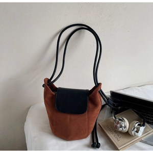 Détail du sac seau vintage en daim marron avec rabat en cuir noir et double bandoulière