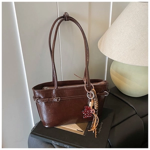 Detail of dark brown glossy patent leather shoulder bag with chic leopard charm