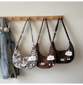 Detailansicht dreier Halbmond-Taschen mit Paisleymuster und flauschigen Wolken-Anhängern