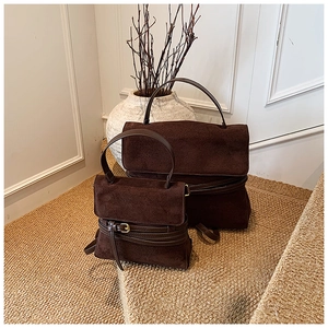 Detalle de bolsos de ante marrón oscuro con hebillas metálicas y diseño de correas
