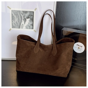 Close-up of the vintage brown suede texture and minimalist shoulder strap on the tote bag