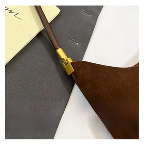 Close-up of matte gold hardware and dark brown suede material on the tote shoulder bag