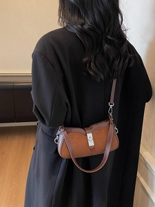 Borsa vintage marrone in pelle scamosciata con impunture a rombi su un cappotto nero di lana