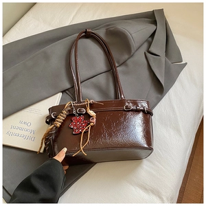 Detail of dark brown glossy leather bucket bag with red leopard heart and tassel