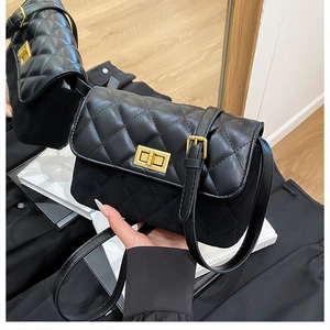 Detail of classic black quilted shoulder bag with vintage gold metal turn-lock closure
