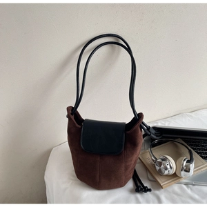 Détail du sac seau en daim marron foncé avec rabat en cuir et fine bandoulière noire