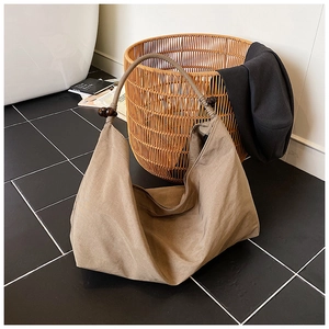 Détail du sac cabas en toile kaki avec perles en bois marron et texture plissée élégante