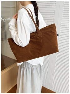 Detailed side view of large brown suede tote bag worn by a model for daily commute