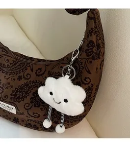 Nahaufnahme eines flauschigen Taschenanhängers mit gestreiften Beinen an einer Paisley-Tasche