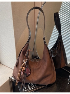 Sac hobo en daim marron foncé avec breloques à franges et ours léopard sur un support