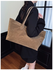 Detail view of large brown suede tote bag featuring visible stitching and matte texture