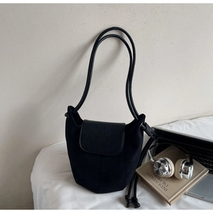 Sac seau noir mat avec fines bretelles sur un lit avec ordinateur et casque