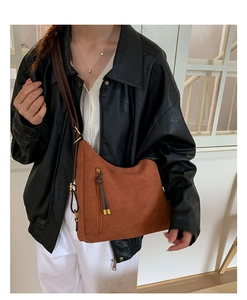 Detail of matte caramel brown half-moon crossbody bag with decorative fringe and metal zipper