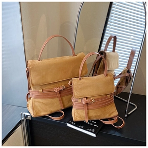 Detalle de bolsos bandolera de ante mate en dos tamaños con correas decorativas y hebillas de metal
