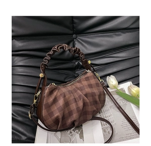 Detailed view of brown checkered dumpling bag with ruffled handles and adjustable strap