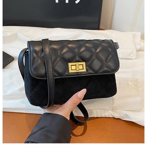 Detail of black quilted crossbody bag with gold twist lock and mixed leather texture