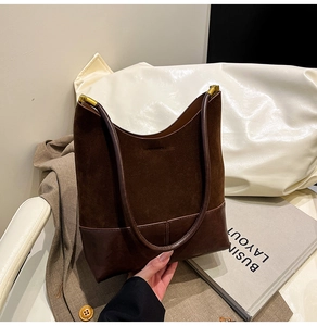 Détail des coutures en daim rétro et cuir lisse sur un grand sac cabas fourre-tout