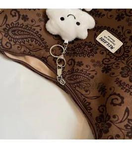 Detailansicht der braunen Vintage-Tasche mit Metallreißverschluss und Plüschanhänger
