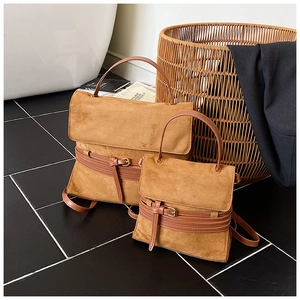 Primer plano de dos bolsos de cuero marrón mate con hebillas metálicas en un estudio elegante