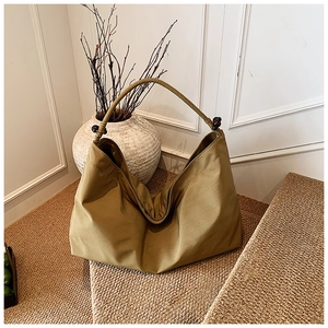 Détail du sac cabas kaki en toile avec perles en bois foncées sur la bandoulière de l'épaule