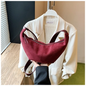 Detail of burgundy suede crescent bag showing premium matte texture and wide strap