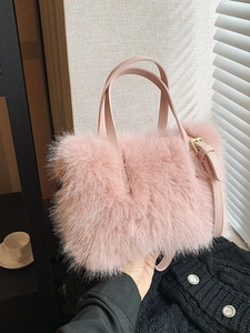 Pink plush faux fur tote bag with adjustable shoulder strap shown in lifestyle hand-carry view