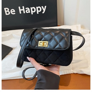 Detail shot of the black quilted small square bag with golden twist lock and mixed textures