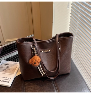 Detailed macro view of large brown tote bag with leather texture and fashion metal plate