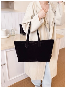 Detailed view of a black frosted tote bag worn by a model in a minimalist setting