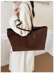 Detail of dark brown suede tote bag with slim shoulder straps worn over a beige trench coat