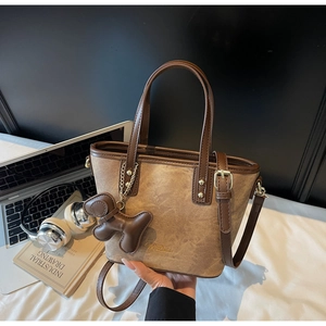 Detail view of brown textured crossbody tote bag with cute pendant and long strap
