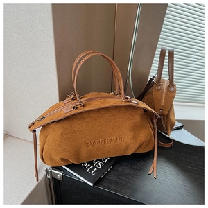 Detailed view of brown suede handbag with embossed logo and decorative leather tassels