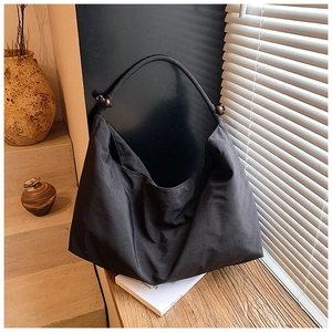 Détail du sac hobo en toile noire avec des perles décoratives en bois sur la bandoulière